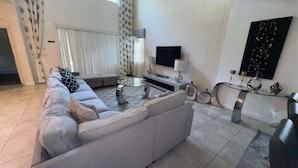 Ein modernes Wohnzimmer mit einer Couch, einem Couchtisch, einem Fernseher und Dekoelementen.
