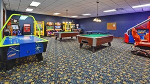 Ein Raum mit Billardtischen, Spielautomaten und einem gemusterten Teppich.