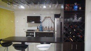 A kitchen with a bar area, wine rack, and various kitchen appliances.