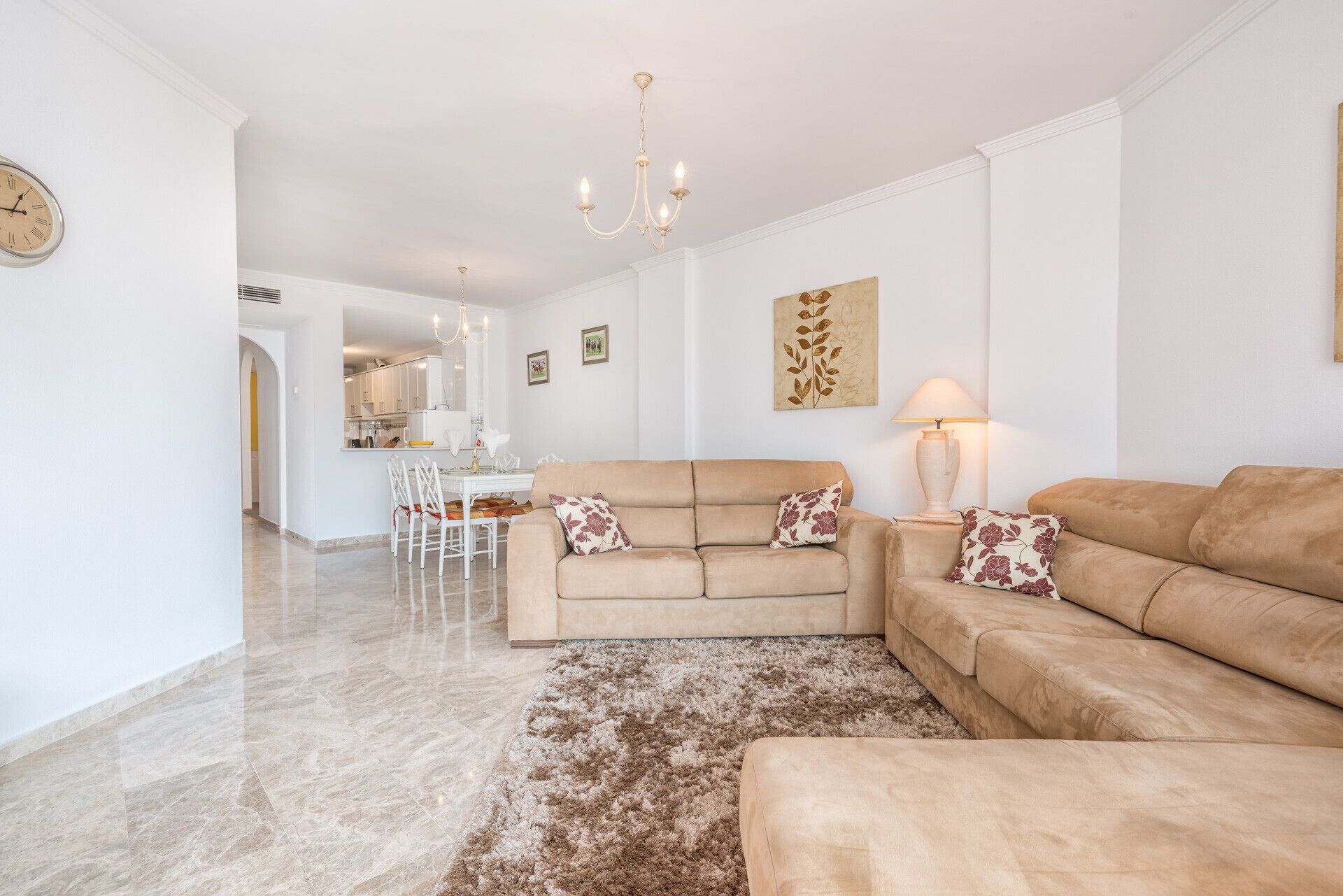 Una sala de estar con un sofá beige, una alfombra mullida y una araña.