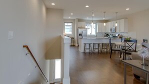 A spacious kitchen with a central island, bar stools, and a dining area with a table and chairs.