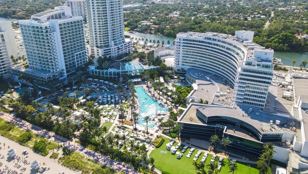 A resort with multiple high-rise buildings, a central pool area, and a beach.