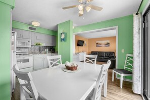 A modern kitchen with white cabinets, a dining table with chairs, and a ceiling fan. - A448 at The Myrtle Beach Resort (Myrtle Beach)