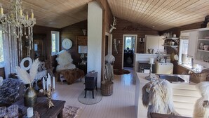 A cozy cabin interior with wooden beams, a chandelier, rustic decor, and a fireplace. - High standard cabin with view, hiking and fishing Ocean boat rental possible (Raudsand)
