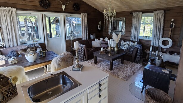 A cozy cabin interior with a wooden interior, a dining area, a kitchen with a sink, and a fireplace. - High standard cabin with view, hiking and fishing Ocean boat rental possible (Raudsand)