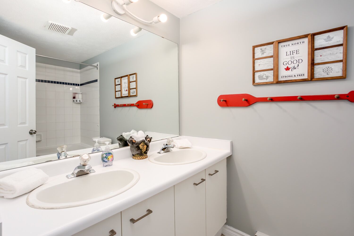 Une salle de bain avec deux lavabos, un miroir et une pagaie rouge accrochée au mur.