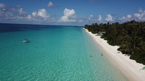 Una playa con agua turquesa cristalina, una orilla de arena blanca y una hilera de palmeras.