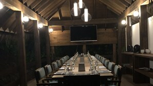 Una larga mesa de comedor preparada para una comida en una habitación rústica de madera con un televisor de pantalla plana montado en la pared.