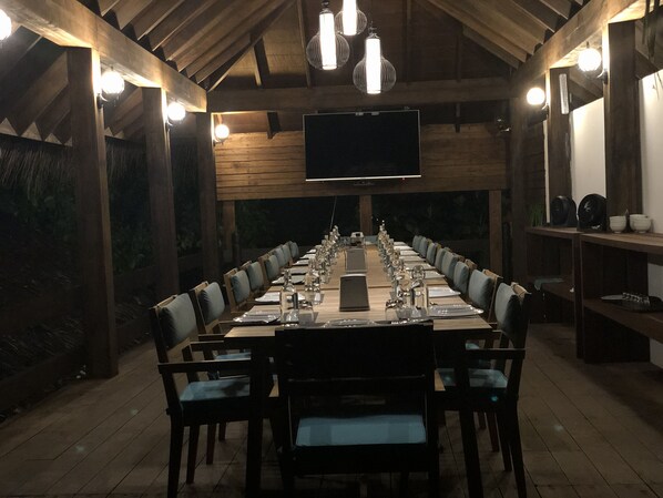 Una larga mesa de comedor preparada para una comida en una habitación rústica de madera con un televisor de pantalla plana montado en la pared.