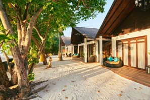 A resort with outdoor seating areas, wooden structures, and a sandy pathway.