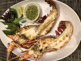 Un plato con un langostino cocido, un cuenco pequeño de salsa y algunas verduras.