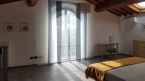 Ein Schlafzimmer mit Bett, Schreibtisch und Stuhl. Ein Fenster bietet einen Blick nach draußen.