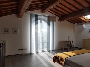Ein Schlafzimmer mit Bett, Schreibtisch und Stuhl. Ein Fenster bietet einen Blick nach draußen.