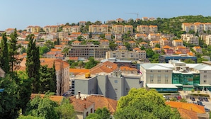 Un quartier résidentiel comprenant plusieurs immeubles d’appartements, un bâtiment imposant portant une enseigne indiquant « PEMO CENTAR », et des espaces verts environnants.