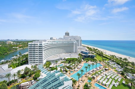 A hotel with a large pool area, multiple swimming pools, and a beach view.