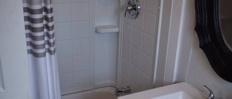 A bathroom with a shower, a sink, and a mirror.