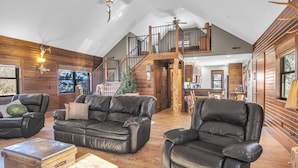 A spacious living area with leather sofas, a wooden coffee table, and a staircase leading to an upper level.