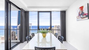 A modern dining area with a large table, chairs, and a plant centerpiece. - Circle on Cavill Ocean & River Views (Surfers Paradise)