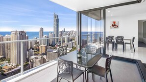 A balcony with a glass table and chairs, overlooking a cityscape and the ocean. - Circle on Cavill Ocean & River Views (Surfers Paradise)