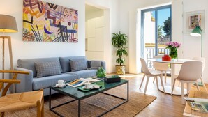 Een moderne woonkamer met een bank, salontafel en een eethoek met stoelen en een tafel.