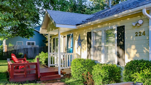 Una casa con un portico, il numero 224 sul lato e una sedia rossa all'esterno.