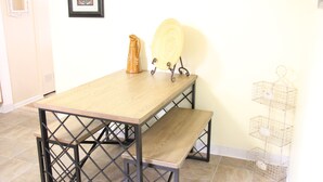 Un tavolo in legno con una panca, una brocca di ceramica e un quadro appeso al muro.
