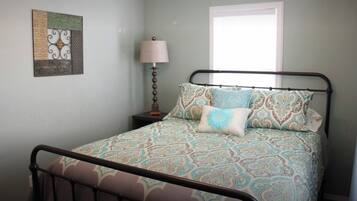 A bedroom with a bed, a nightstand, a lamp, and a window.