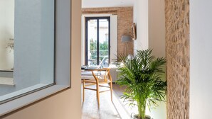 A modern interior with a wooden floor, a potted plant, and a dining area with a table and chairs.