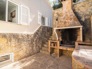 A stone fireplace with a brick surround, a stone wall, and a window with shutters.