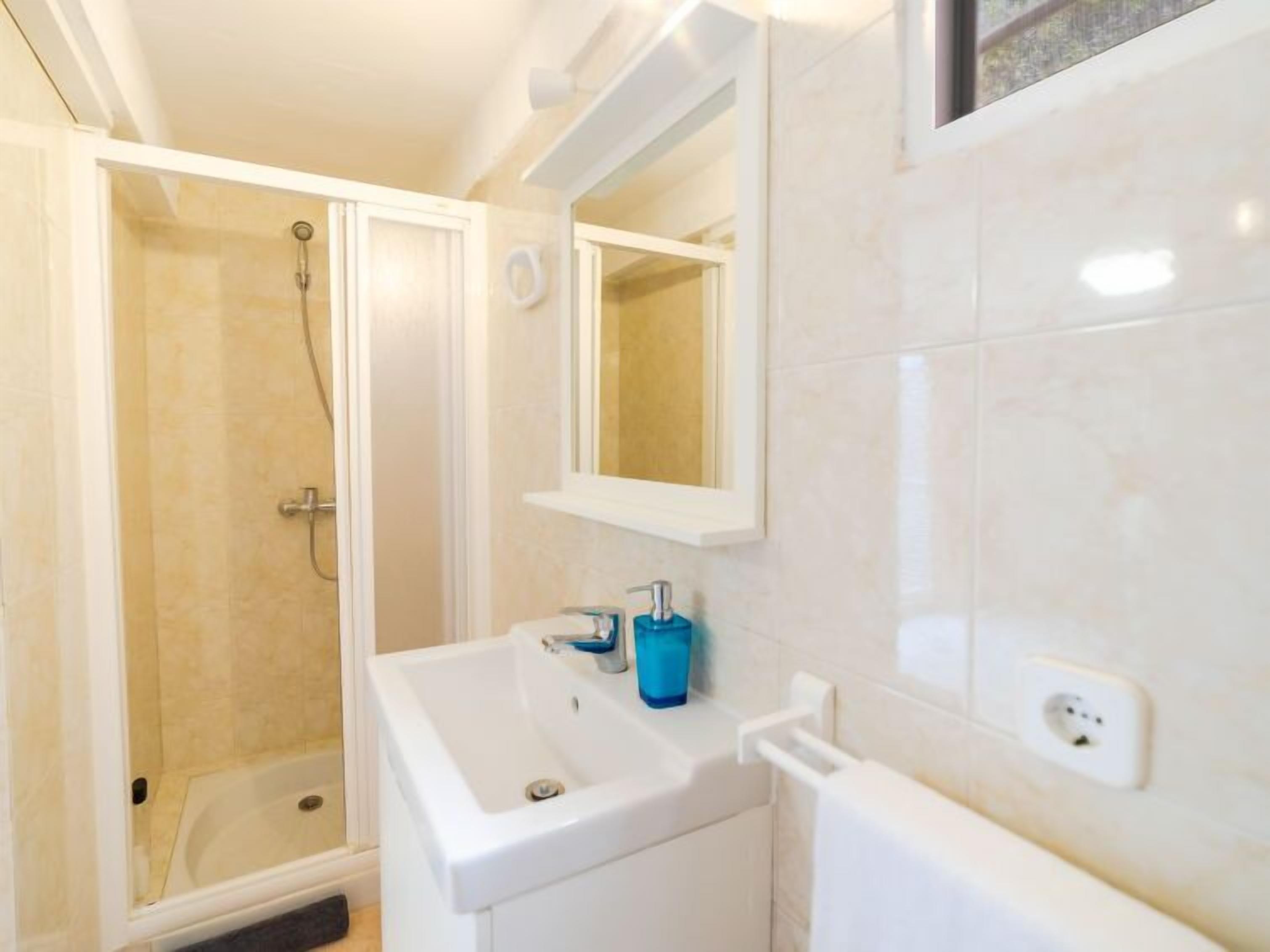 Ein Badezimmer mit Dusche, Waschbecken und Spiegel.