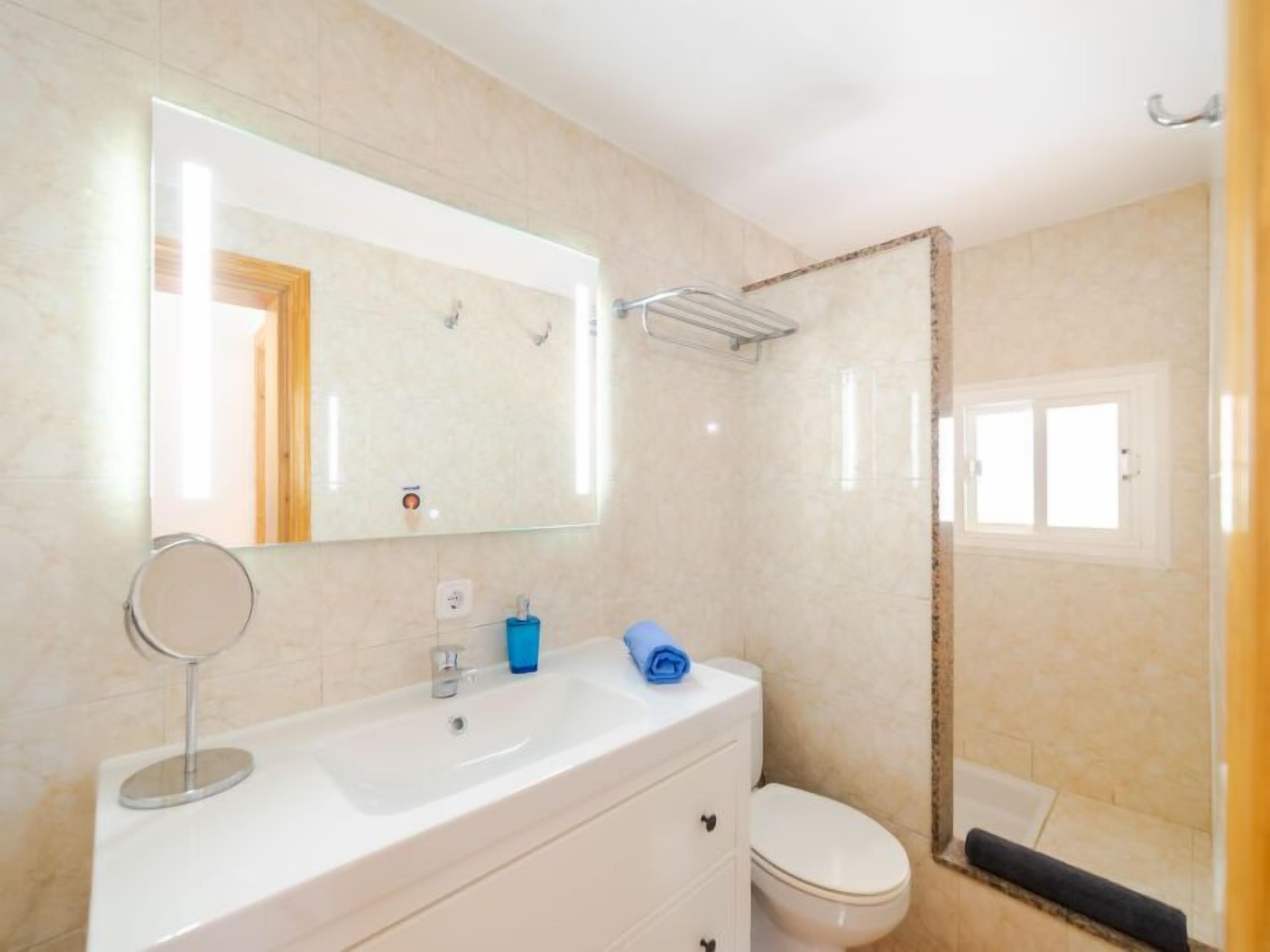 A bathroom with a white sink, a mirror, a toilet, and a shower area.