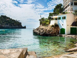 A coastal building with a staircase leading to a green door, situated on a rocky shore with clear water. - Cala Santanyí Beach House JM by Interhome (Cala Santanyí-Figuera-Llombards)