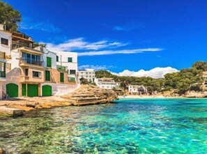A coastal building with multiple floors, large windows, and green doors. - Cala Santanyí Beach House JM by Interhome (Cala Santanyí-Figuera-Llombards)