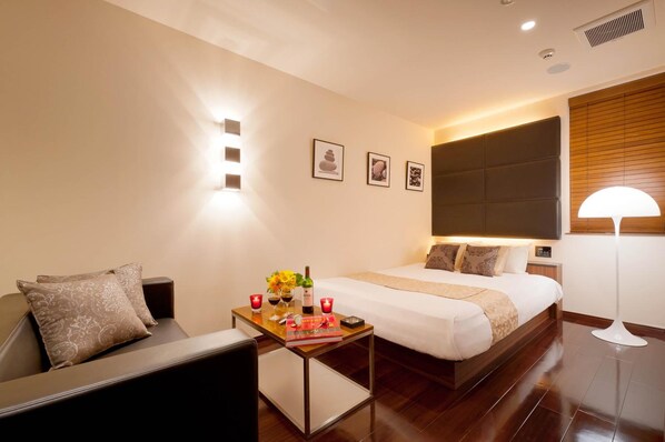 A hotel room with a bed, a bedside table with candles, and a lamp.