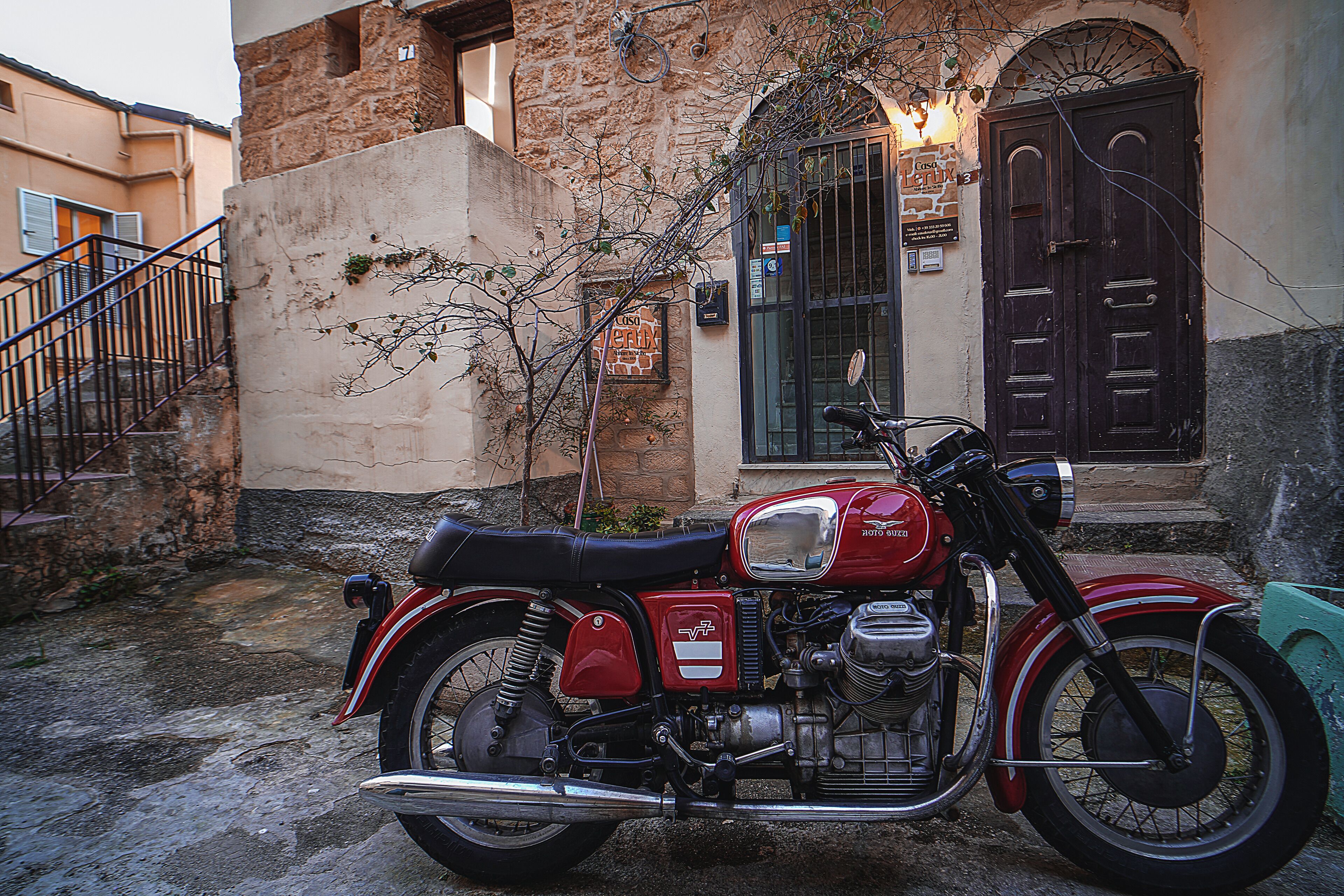 Una motocicletta d'epoca parcheggiata di fronte a un edificio con facciata in pietra e porta in legno.