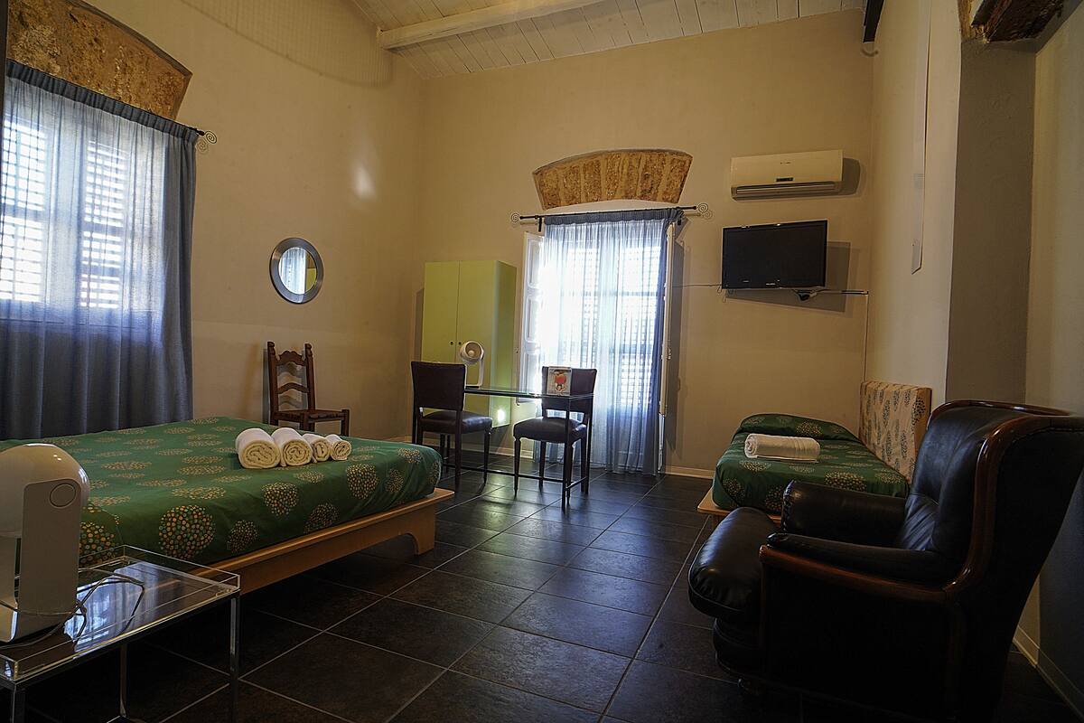 A hotel room with a bed, a chair, a desk, and a television.