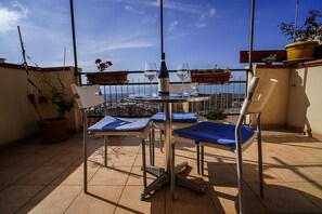 A balcony with a table, two chairs, a bottle of wine, and two glasses. - Casa Lerux (Agrigento)