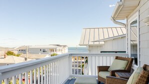 A balcony with wicker furniture and a view of the ocean.