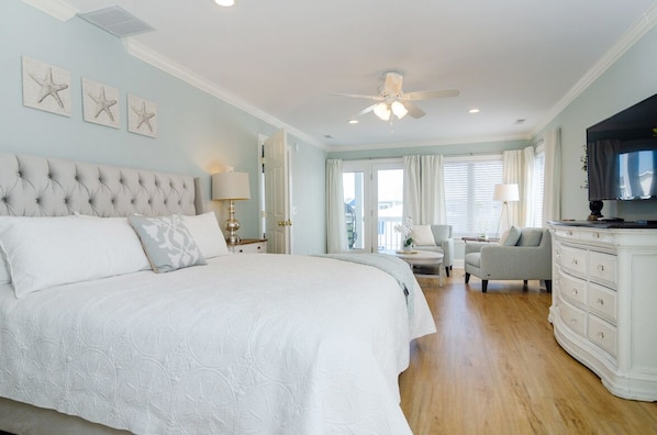 A spacious bedroom with a large bed, a ceiling fan, and a television.