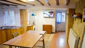 Une cuisine avec une table en bois, un évier et un téléviseur fixé au mur.