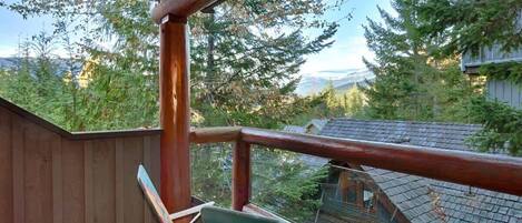 A wooden deck with a view of a forest and mountains.