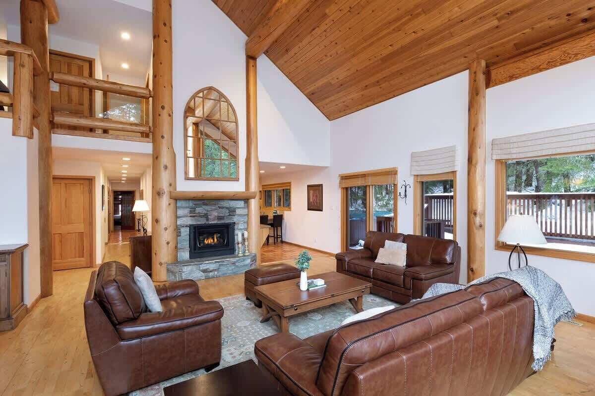 A spacious living area with a fireplace, leather sofas, and a wooden ceiling.