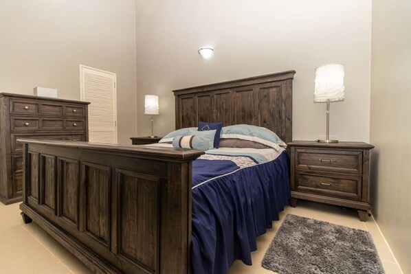 A bedroom with a large wooden bed, two bedside tables, a nightstand, and a gray rug.