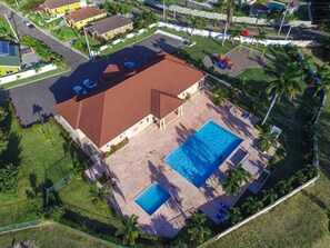 A residential property with a swimming pool, a fenced yard, and a red-roofed building.