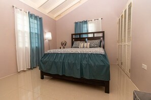 A bedroom with a bed, curtains, a bedside lamp, and a closet.