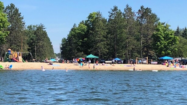 A beach with a playground and umbrellas. - Beautiful Cottage Just minutes from The Twin Lakes & Beach  (Lewiston)