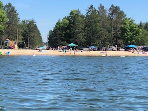 Relax by the serene lake with a sandy beach area, playground and umbrellas for a family-friendly getaway.