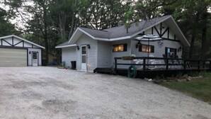 A single-story house with a gravel driveway, a fenced yard, and a garage. - Beautiful Cottage Just minutes from The Twin Lakes & Beach  (Lewiston)
