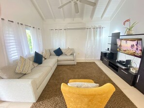 A living room with a sofa, yellow armchair, and a TV stand.