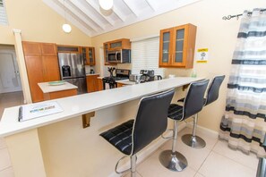 Une cuisine moderne dotée d’un îlot central, d’appareils électroménagers en acier inoxydable et d’armoires en bois.